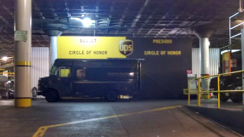 Two “Circle of Honor” boards, one marked Sunset and one Presidio, mounted above a parked UPS truck in a depot.